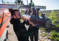 Two team members holding up a sensor torpedo.
