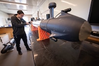 Female engineer examining a sensor torpedo.