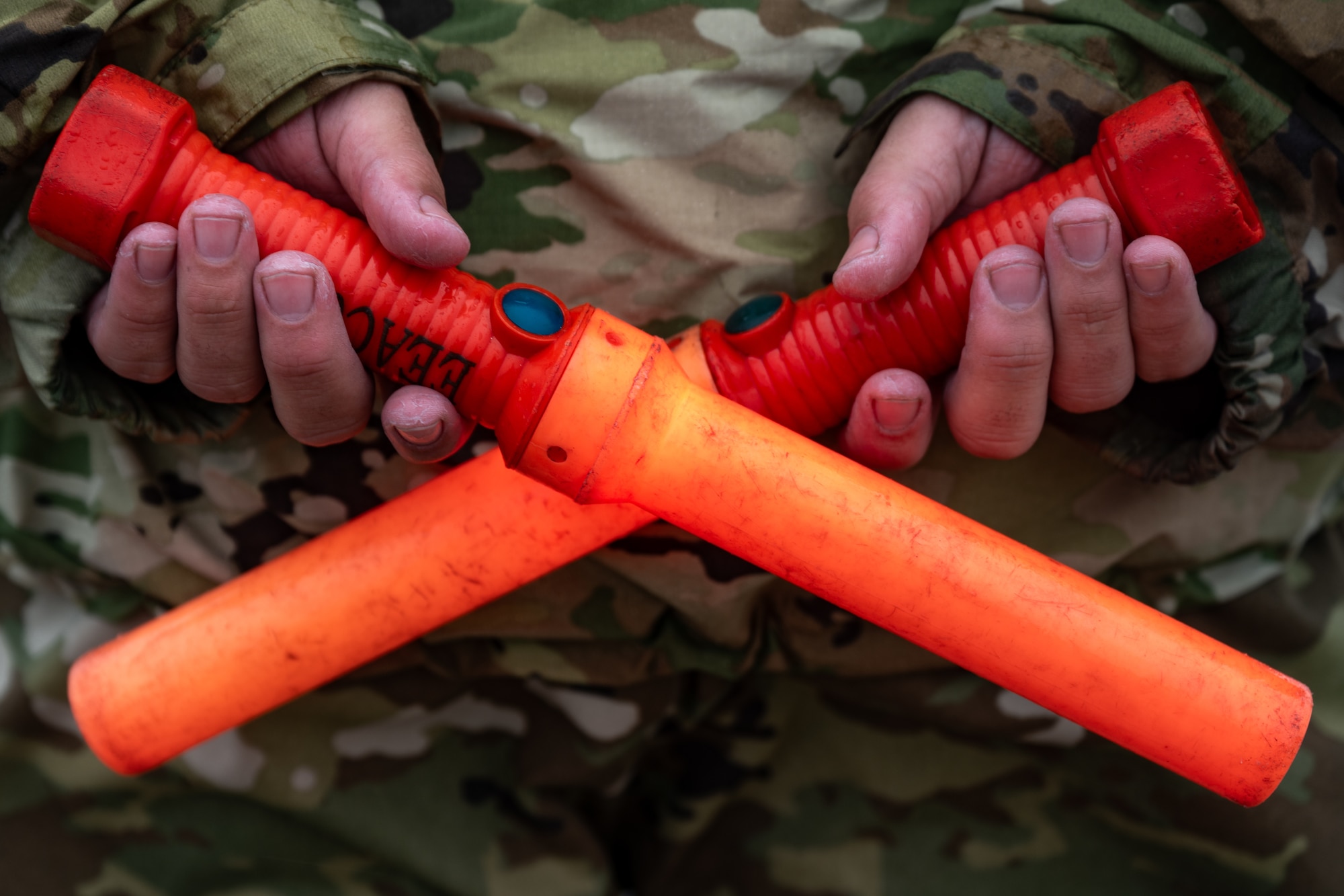 A U.S. Air Force crew chief holds two marshaling wands behind his back like the letter X at Hurlburt Field, Florida, Feb. 19, 2025.