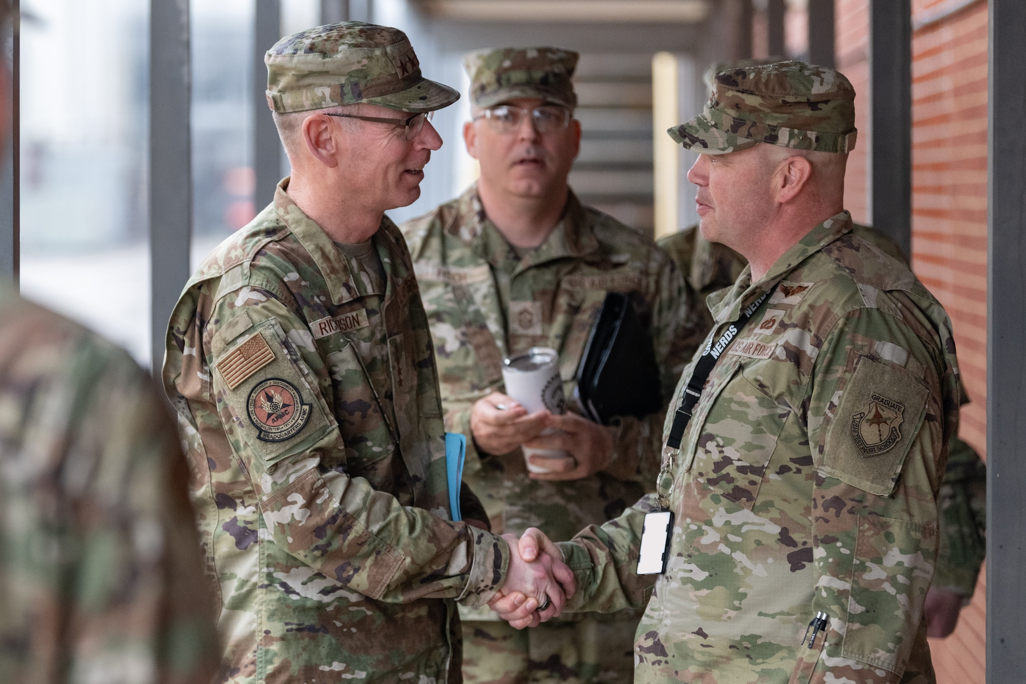 Gen. Duke Z. Richardson, commander of Air Force Materiel Command, left, is greeted by Col. Jason Vap, 804th Test Group commander, during his April 24, 2025, visit to Arnold Air Force Base, Tenn. Also pictured is Chief Master Sgt. Bill Fitch, AFMC Command Chief Master Sergeant, center. Richardson visited Arnold AFB, headquarters of Arnold Engineering Development Complex, headquarters of AEDC, to tour several test facilities, meet with personnel, and receive updates on various programs and projects. (U.S. Air Force photo by Keith Thornburgh) (This image was altered by obscuring badges for security purposes)