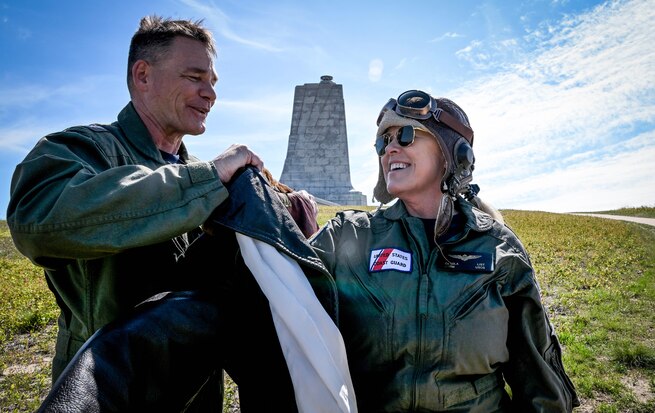 Rear Adm. Christopher Bartz, the 27th Golden Coast Guard Ancient Albatross, places the Ancient Albatross ceremonial flight jacket on Rear Adm. Carola List, the 28th Golden Ancient Albatross, during a visit to Kitty Hawk, North Carolina April 24, 2025. Kitty Hawk is known as the location where the Wright Brothers had the first flight in history, but Coast Guard Life Saving Station crews where also there to help the brothers during that historic event. (U.S. Coast Guard photo by Petty Officer 1st Class Jonathan Lally)
