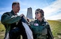 Rear Adm. Christopher Bartz, the 27th Golden Coast Guard Ancient Albatross, places the Ancient Albatross ceremonial flight jacket on Rear Adm. Carola List, the 28th Golden Ancient Albatross, during a visit to Kitty Hawk, North Carolina April 24, 2025. Kitty Hawk is known as the location where the Wright Brothers had the first flight in history, but Coast Guard Life Saving Station crews where also there to help the brothers during that historic event. (U.S. Coast Guard photo by Petty Officer 1st Class Jonathan Lally)