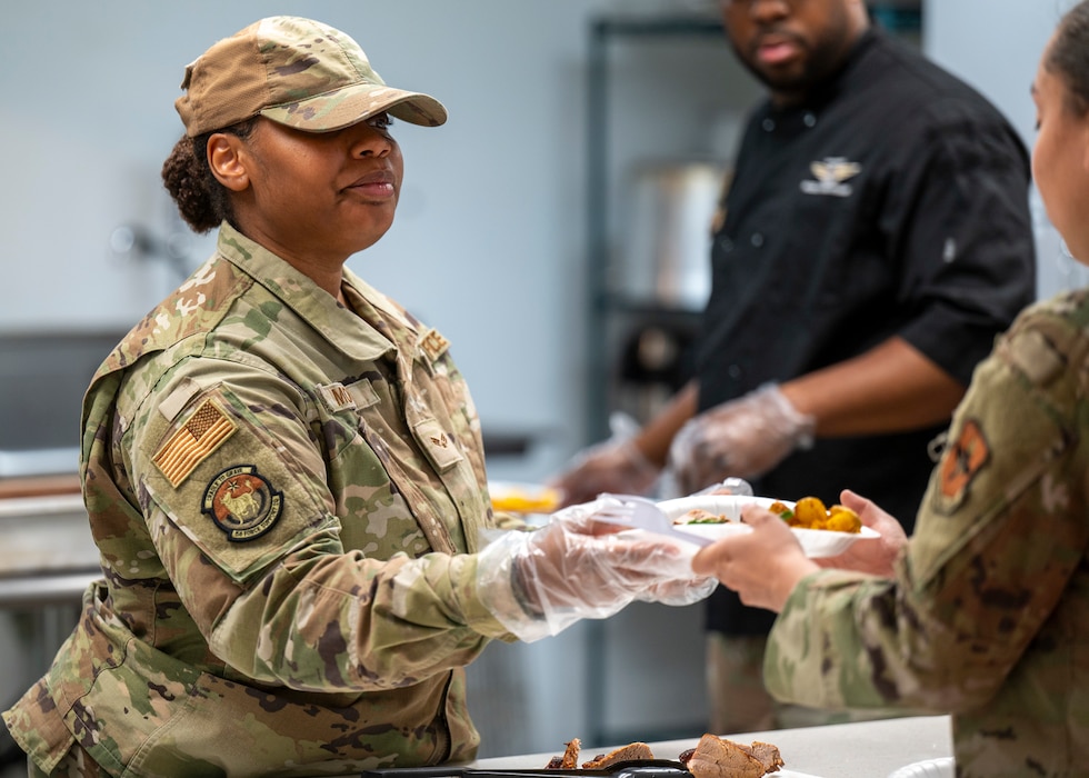 U.S. Air Force Senior Airman Kaitlyn Moore, 56th Force Support Squadron resource advisor assistant, serves an Airman a plate of food during a dorm cooking class