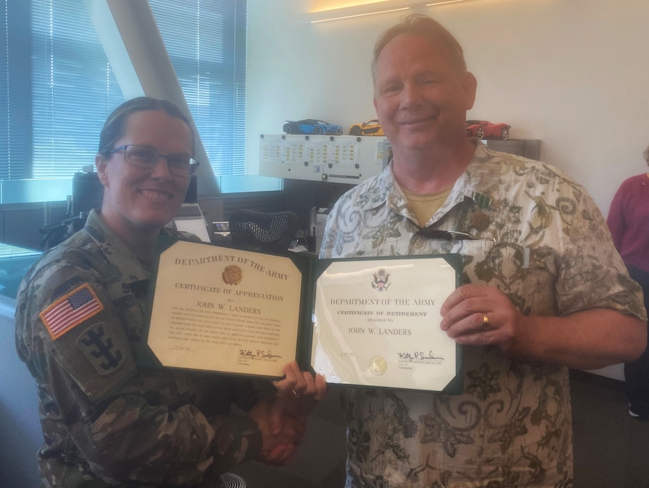 Photo of Security and Law Enforcement Chief John Landers receiving his Certificate of Retirement from Seattle District Commander Kathryn Sanborn during the April employee potluck. Landers retires April 30, 2025, after 39 years of public service.