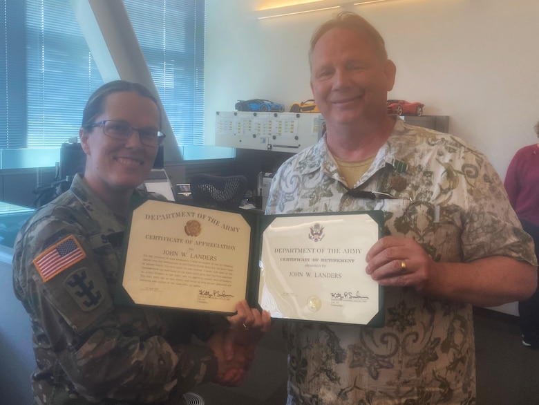 Photo of Security and Law Enforcement Chief John Landers receiving his Certificate of Retirement from Seattle District Commander Kathryn Sanborn during the April employee potluck. Landers retires April 30, 2025, after 39 years of public service.