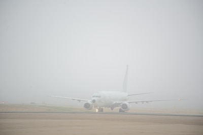 Aircraft 432 emerges from the low visibility after its return from a mission flight.