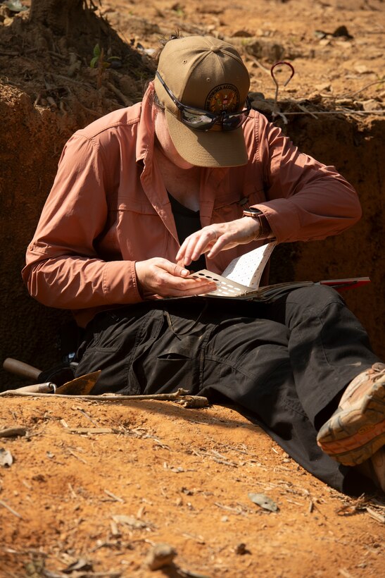 Dr. Larkin Kennedy, scientific recovery expert, Defense POW/MIA Accounting Agency, compares a sample of excavated material with references during a recovery operation in Vietnam, March 12, 2025.