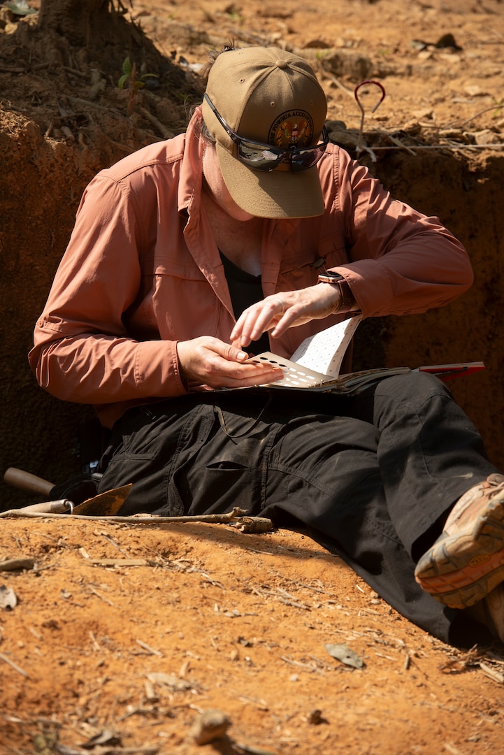 Dr. Larkin Kennedy, scientific recovery expert, Defense POW/MIA Accounting Agency, compares a sample of excavated material with references during a recovery operation in Vietnam, March 12, 2025.