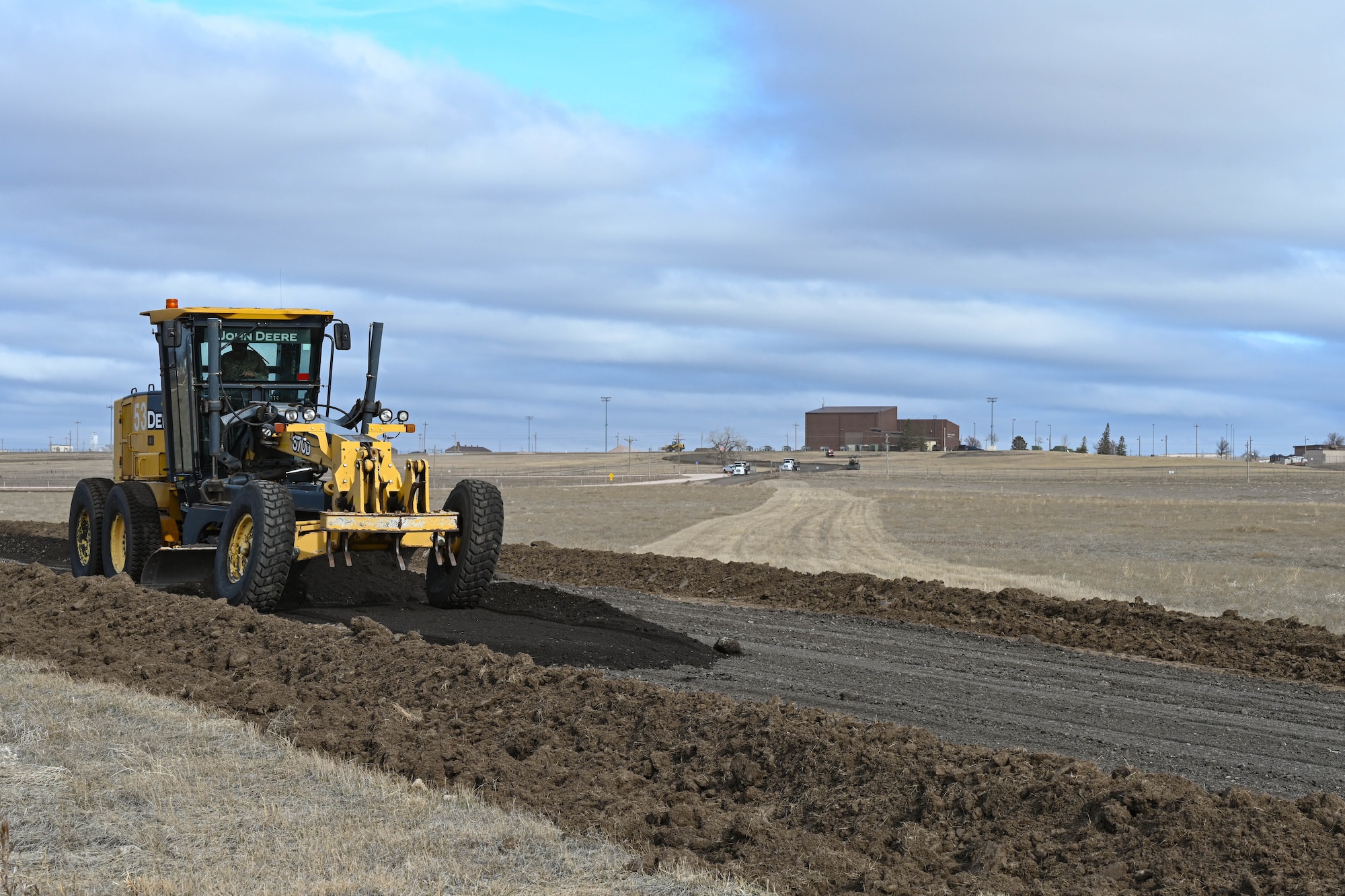 A grader levels crushed asphalt.
