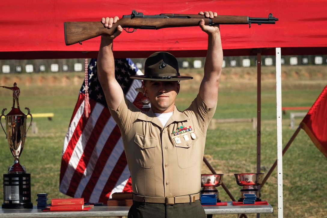U.S. Marine Corps Staff Sgt. Payton Garcia, an expeditionary fuels technician, instructor and competitor with the Marine Corps Shooting Team, Weapons Training Battalion, holds up an M1 Garand rifle during the Marine Corps Championships Award Ceremony hosted by WTBn at Marine Corps Base Quantico, Virginia, April 18, 2025. The M1 Garand rifle was presented to the first-place competitor who attained the highest aggregate score of the Individual Rifle Match and the Individual Pistol Match. (U.S. Marine Corps photo by Cpl. Joshua Barker)