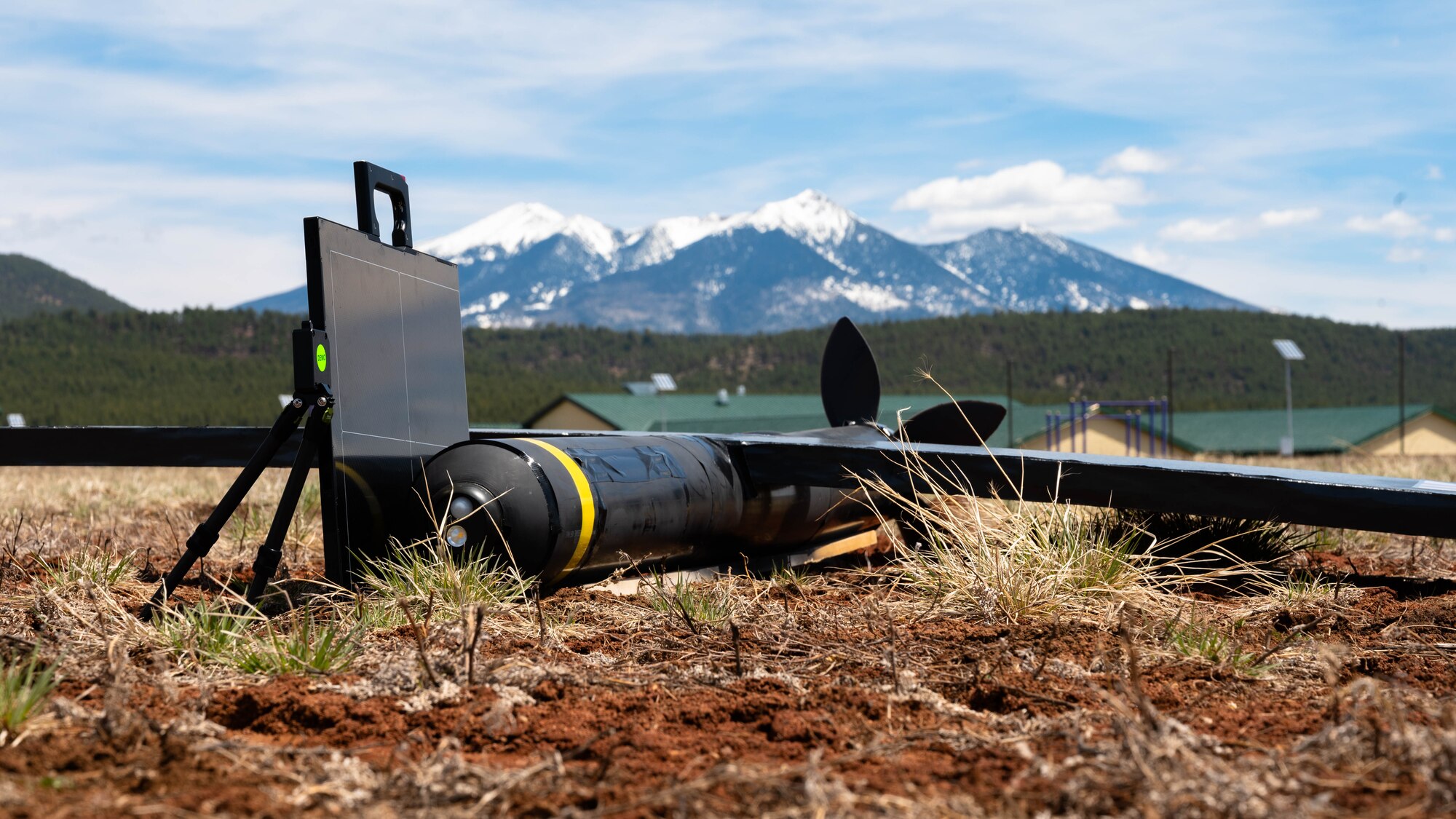 A mock unmanned aerial system with simulated explosives (center) and a new X-ray system (left) are staged on a field during an exercise.