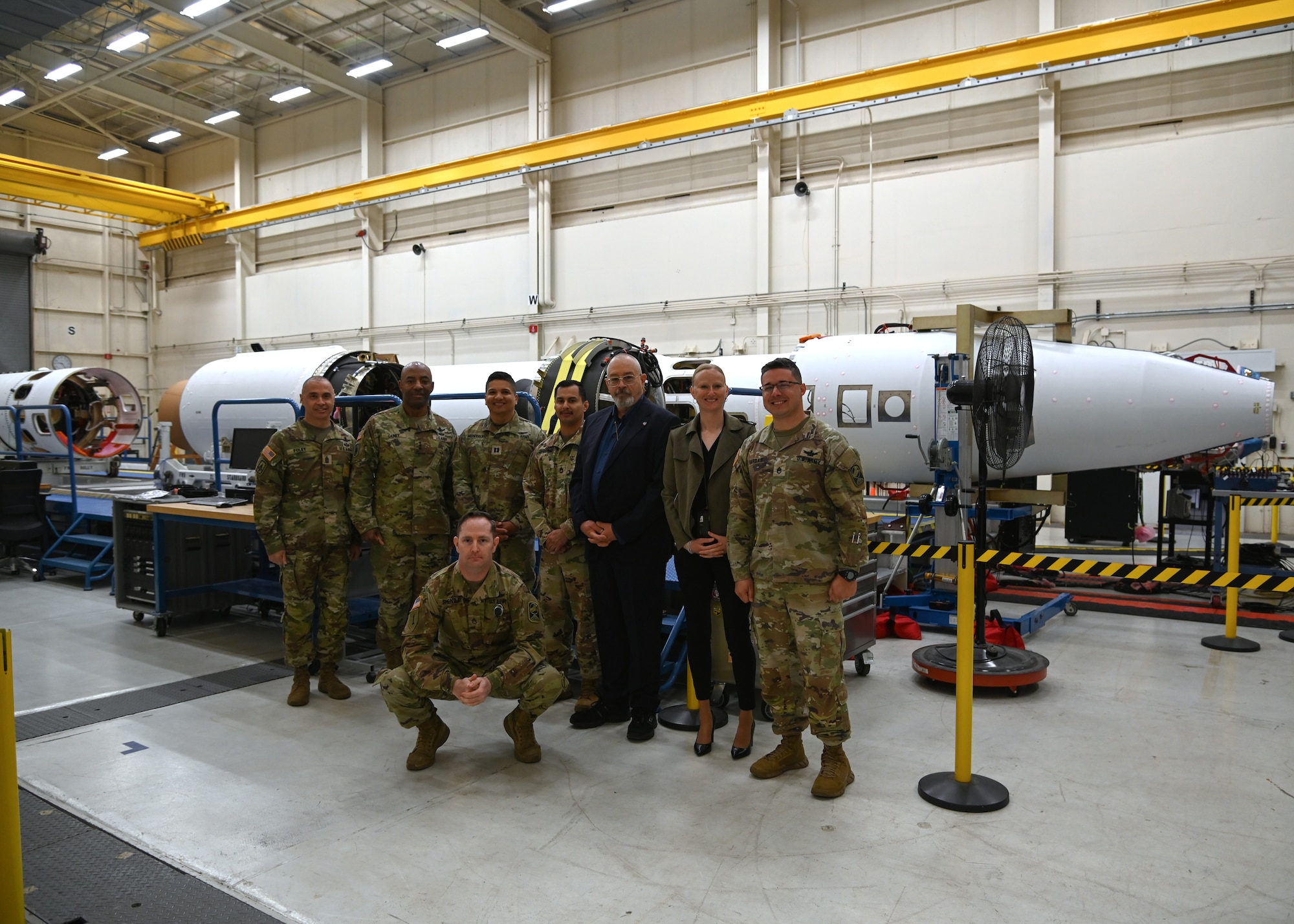 military members posing in front of missile parts in a facility