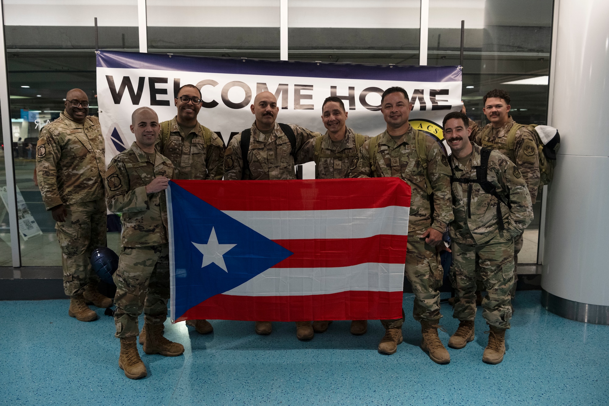 U.S. Airmen with the 141st Air Control Squadron, Puerto Rico Air National Guard, pose for a group photo at the Luis Muñoz Marin International Airport, Carolina, Puerto Rico, April, 18, 2025. Over 50 Airmen with the 141st ACS arrived from a deployment overseas in support of global contingency operations. (U.S. Air National Guard photo by Master Sgt. Rafael Rosa)