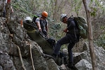 U.S. Army Staff Sgt. Danny Black, left, a team sergeant and U.S. Navy Hospital Corpsman 2nd Class Connor Dougherty, a medic, both with Defense POW/MIA Accounting Agency, lower a Skedco stretcher for a medical evacuation rehearsal during a recovery mission in Laos, Mar. 2, 2025.