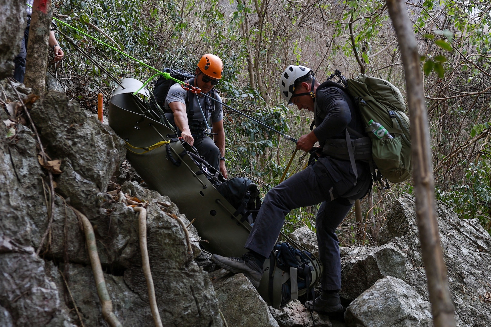 U.S. Army Staff Sgt. Danny Black, left, a team sergeant and U.S. Navy Hospital Corpsman 2nd Class Connor Dougherty, a medic, both with Defense POW/MIA Accounting Agency, lower a Skedco stretcher for a medical evacuation rehearsal during a recovery mission in Laos, Mar. 2, 2025.