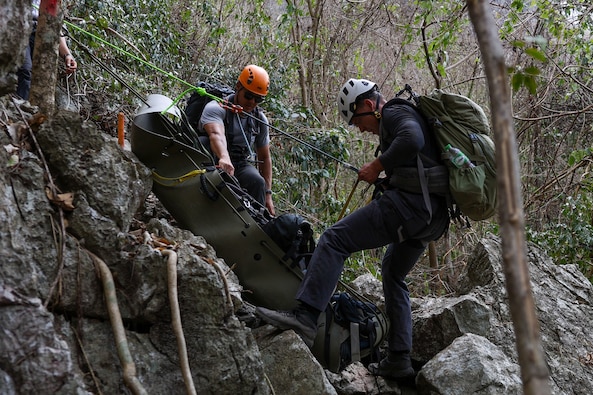 U.S. Army Staff Sgt. Danny Black, left, a team sergeant and U.S. Navy Hospital Corpsman 2nd Class Connor Dougherty, a medic, both with Defense POW/MIA Accounting Agency, lower a Skedco stretcher for a medical evacuation rehearsal during a recovery mission in Laos, Mar. 2, 2025.