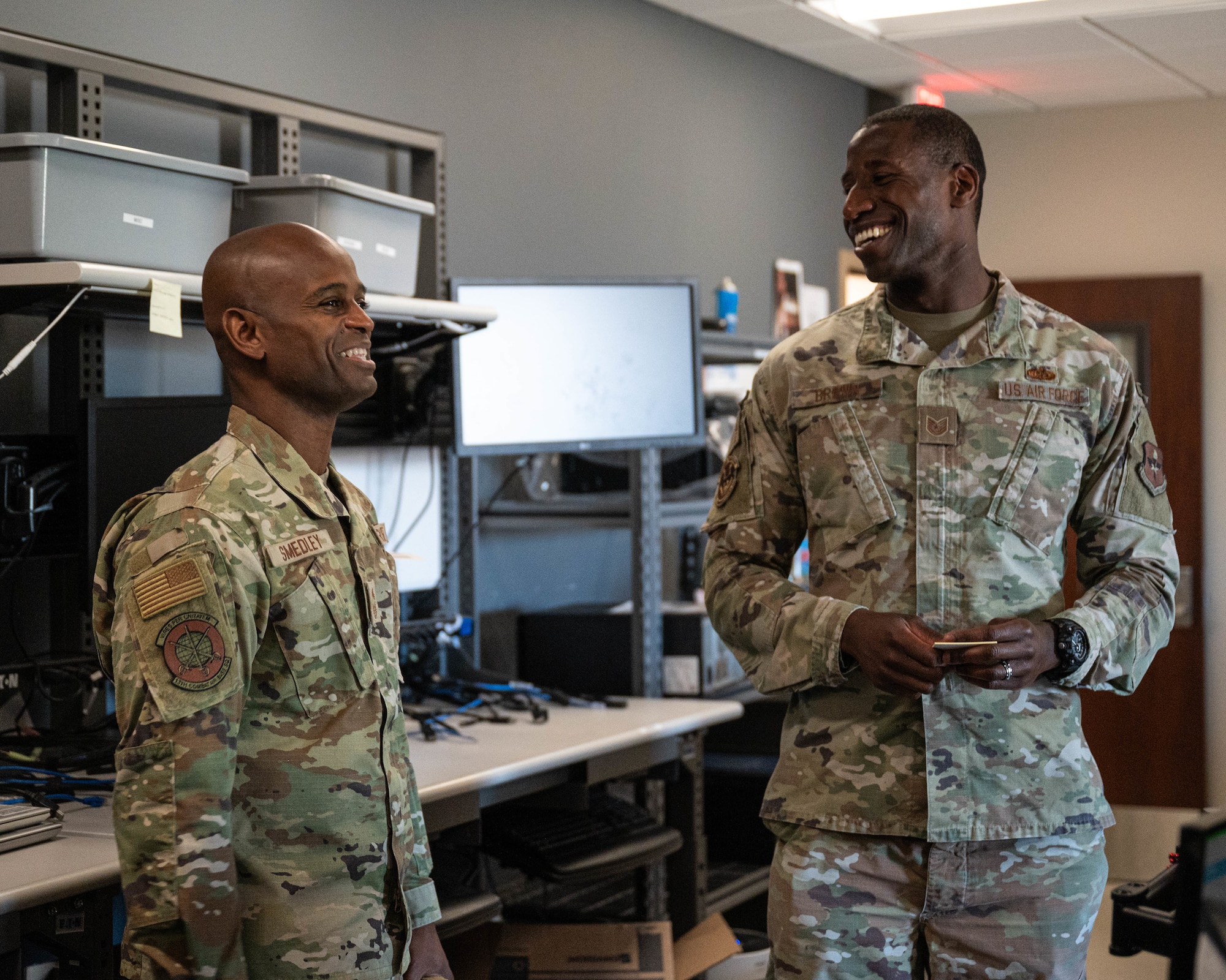 U.S. Air Force Chief Master Sgt. Leray Smedley, 13th Combat Air Base Squadron senior enlisted leader, and Tech. Sgt. Akeem Brown, 56th Communications Squadron client systems technician, laugh together, April 28, 2025, at Luke Air Force Base, Arizona.