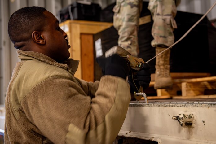 U.S. Air Force Airman 1st Class Andrew Davis 35th Logistic Readiness Squadron (LRS) ground transport operator, tightens a ratchet strap to secure cargo for the Rhino Express program.