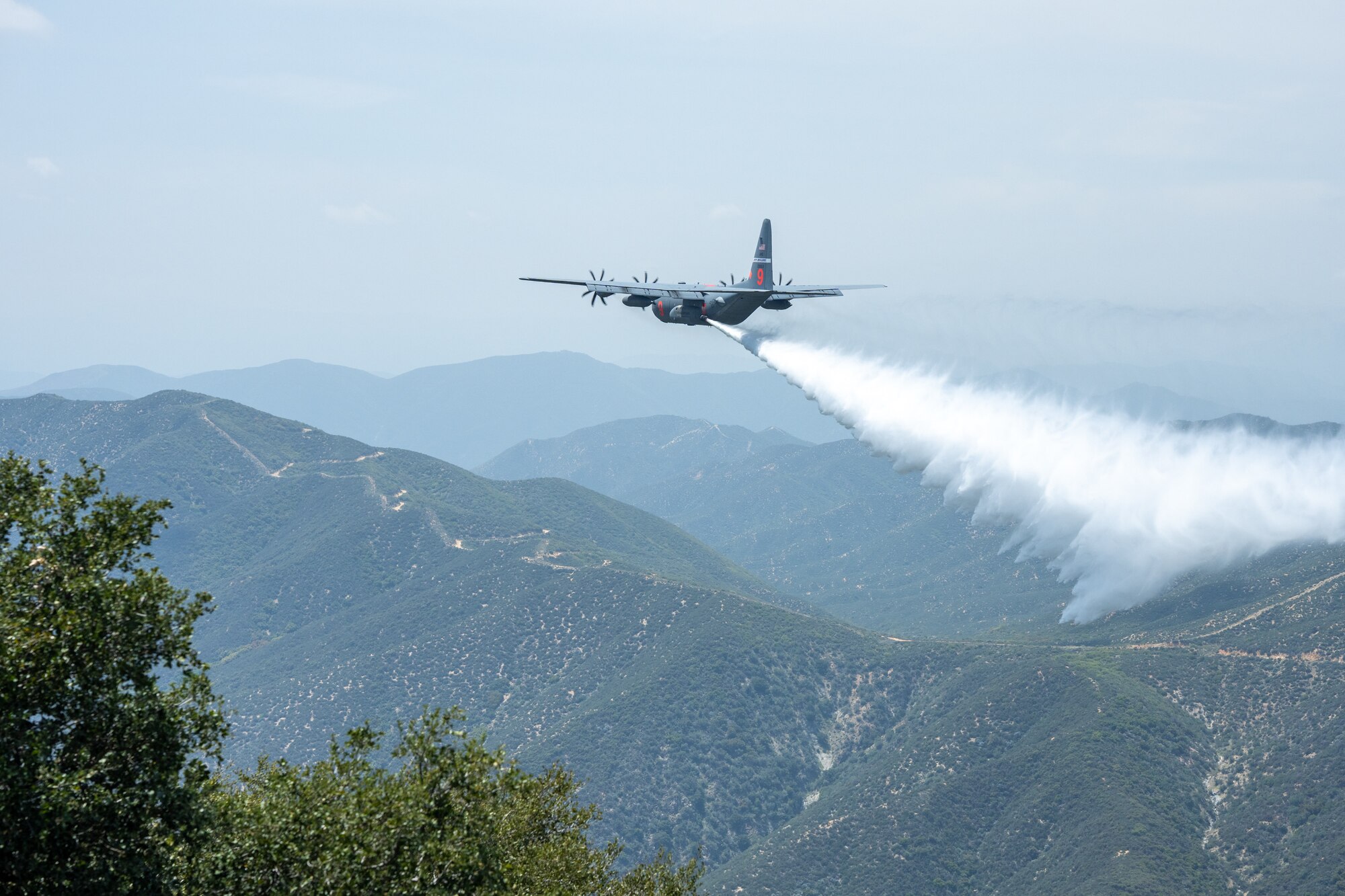 A C-130 (MAFFS 9) from Nevada Air National Guard's 152nd Airlift Wing performs a water drop April 24, 2025, during Modular Airborne Fire Fighting System (MAFFS) Spring Training 2025, hosted by the California Air National Guard's 146th Airlift Wing.