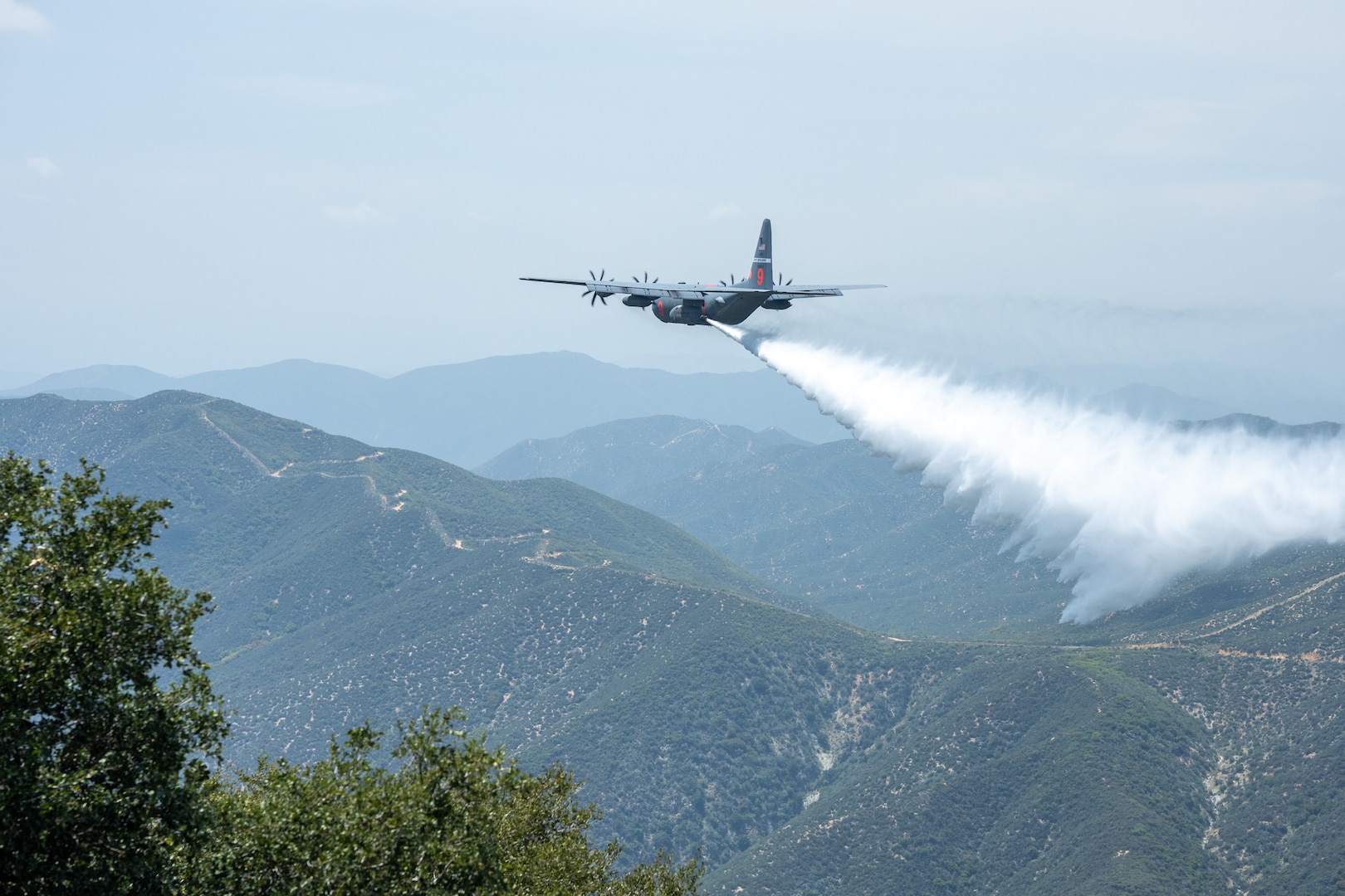 A C-130 (MAFFS 9) from Nevada Air National Guard's 152nd Airlift Wing performs a water drop April 24, 2025, during Modular Airborne Fire Fighting System (MAFFS) Spring Training 2025, hosted by the California Air National Guard's 146th Airlift Wing.