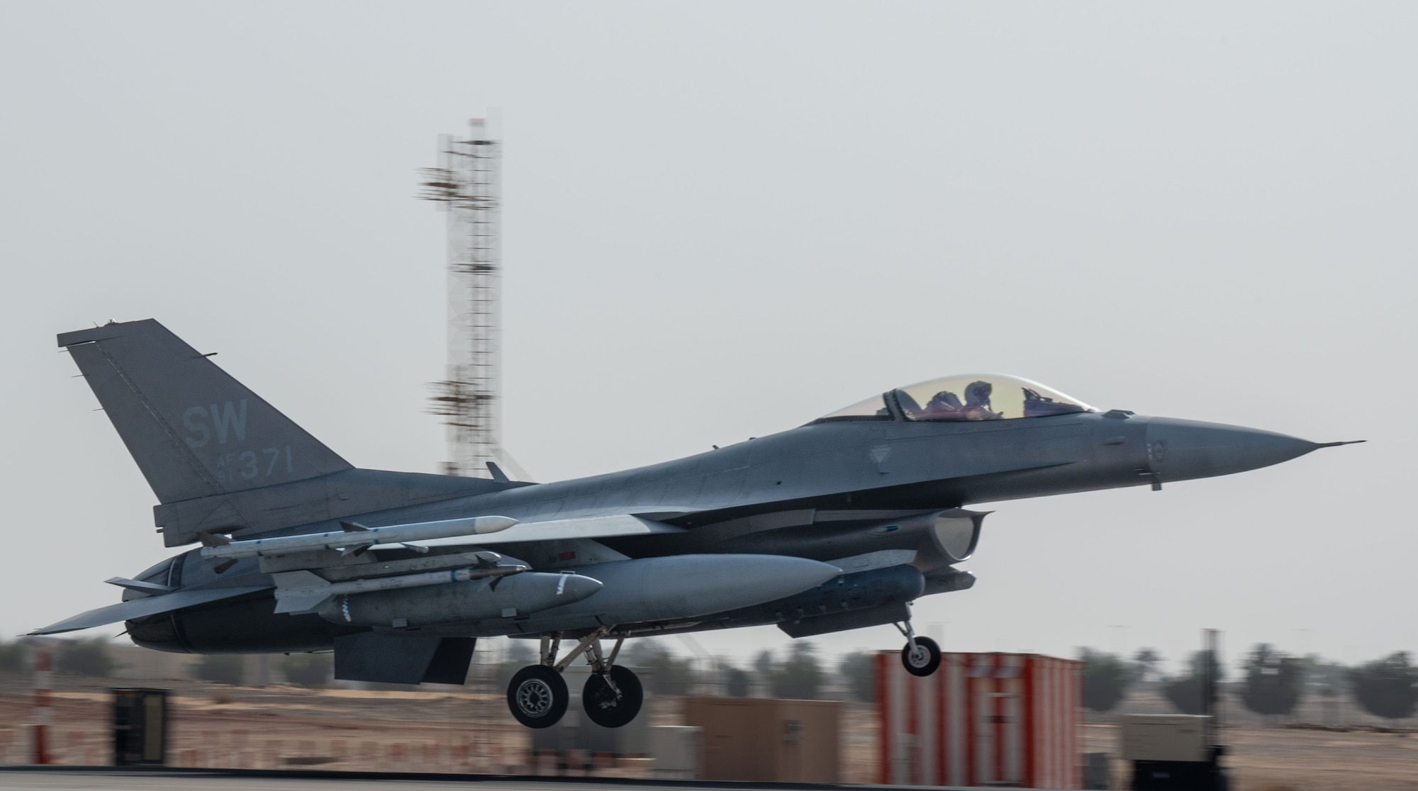An F-16 with landing gear down approaches a runway