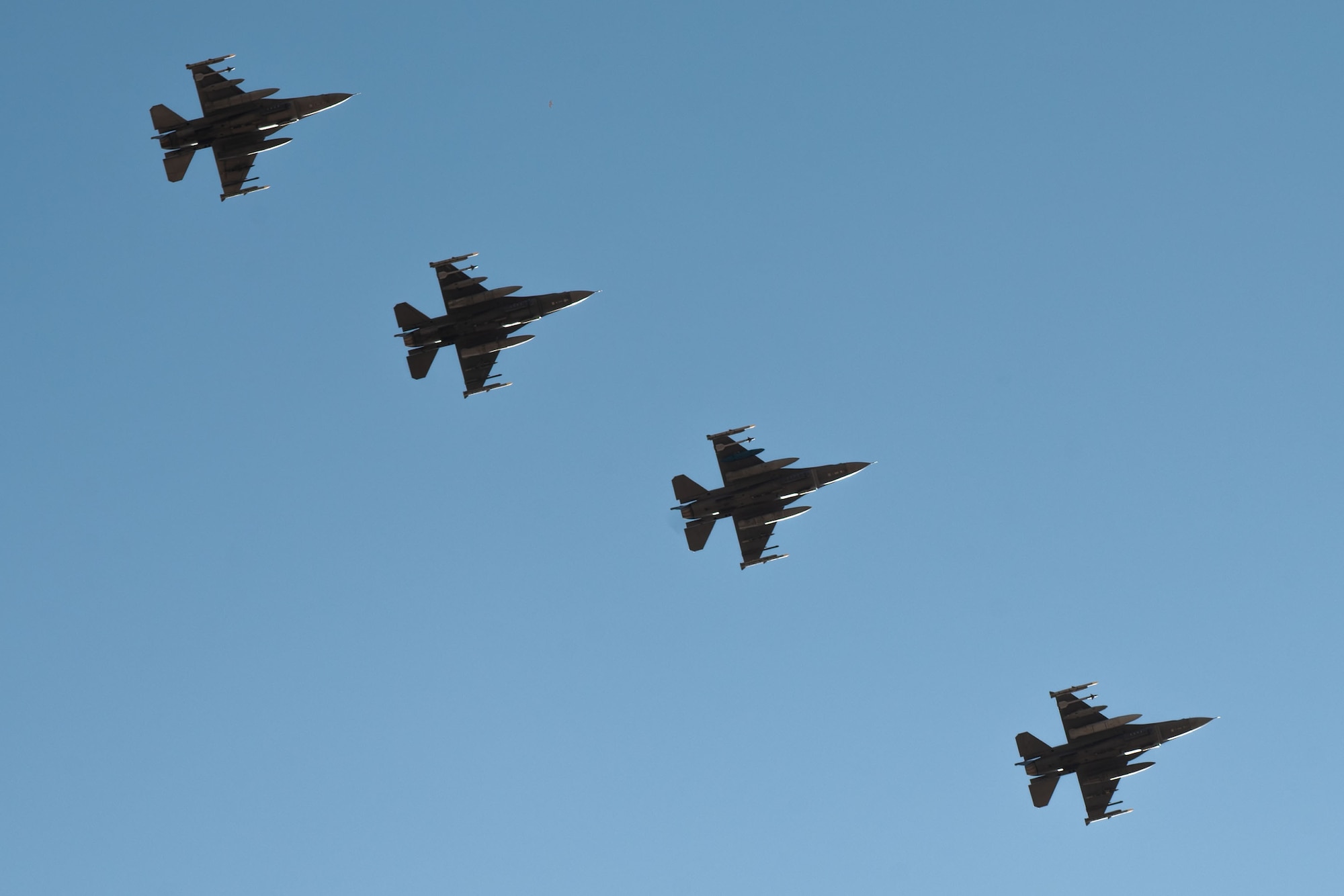 Four F-16s in flight against a blue sky