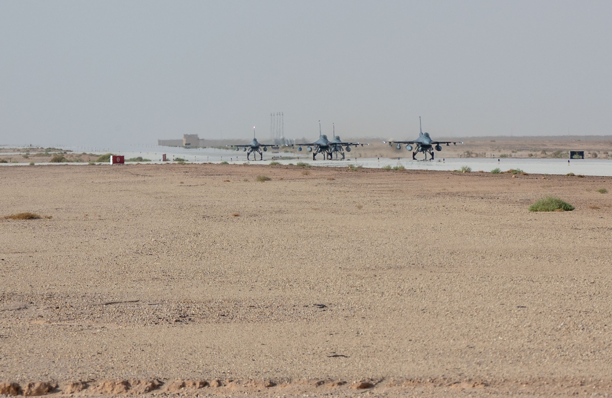 Four F-16s taxi on a runway