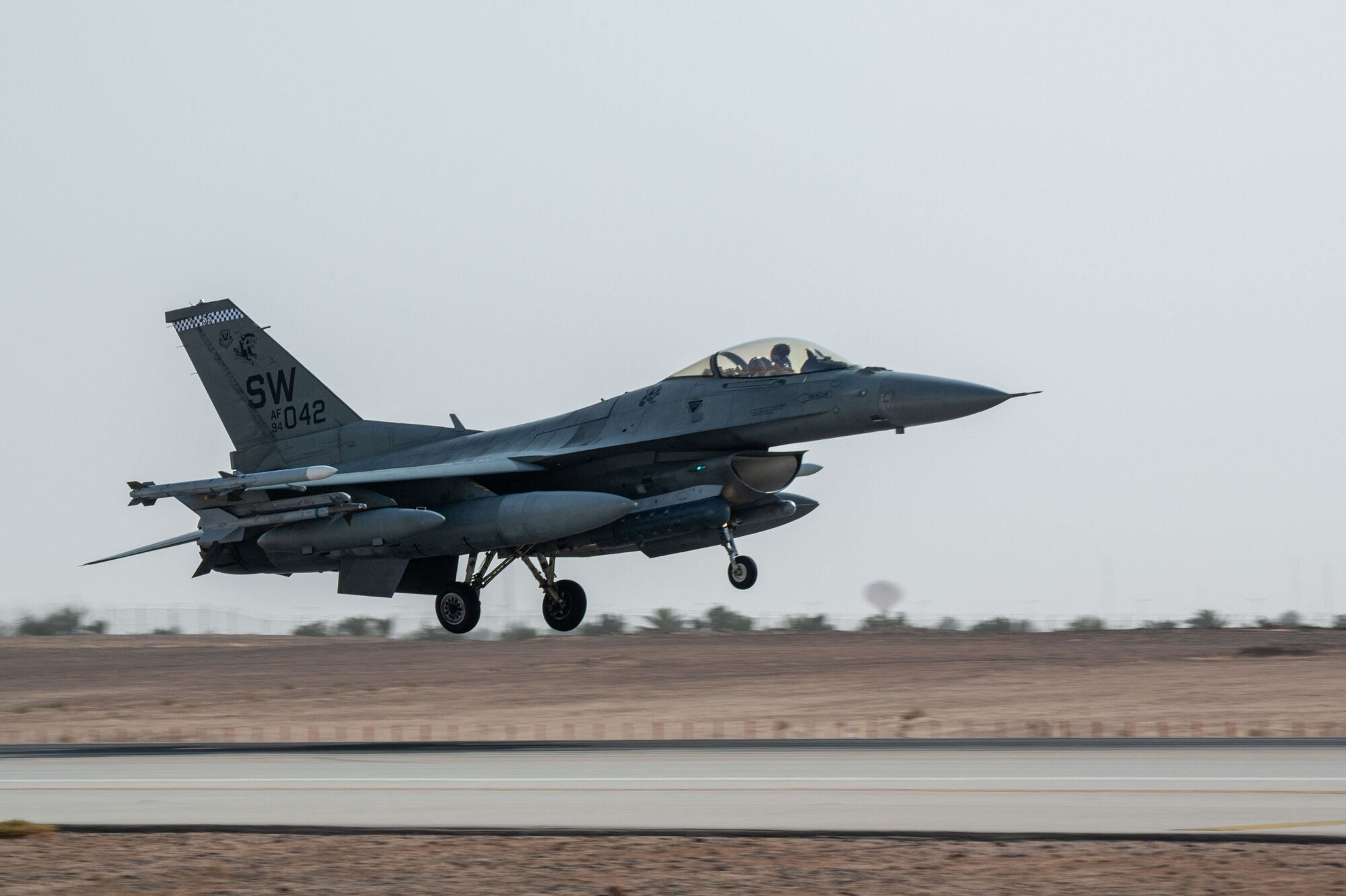 An F-16 with landing gear down approaches a runway