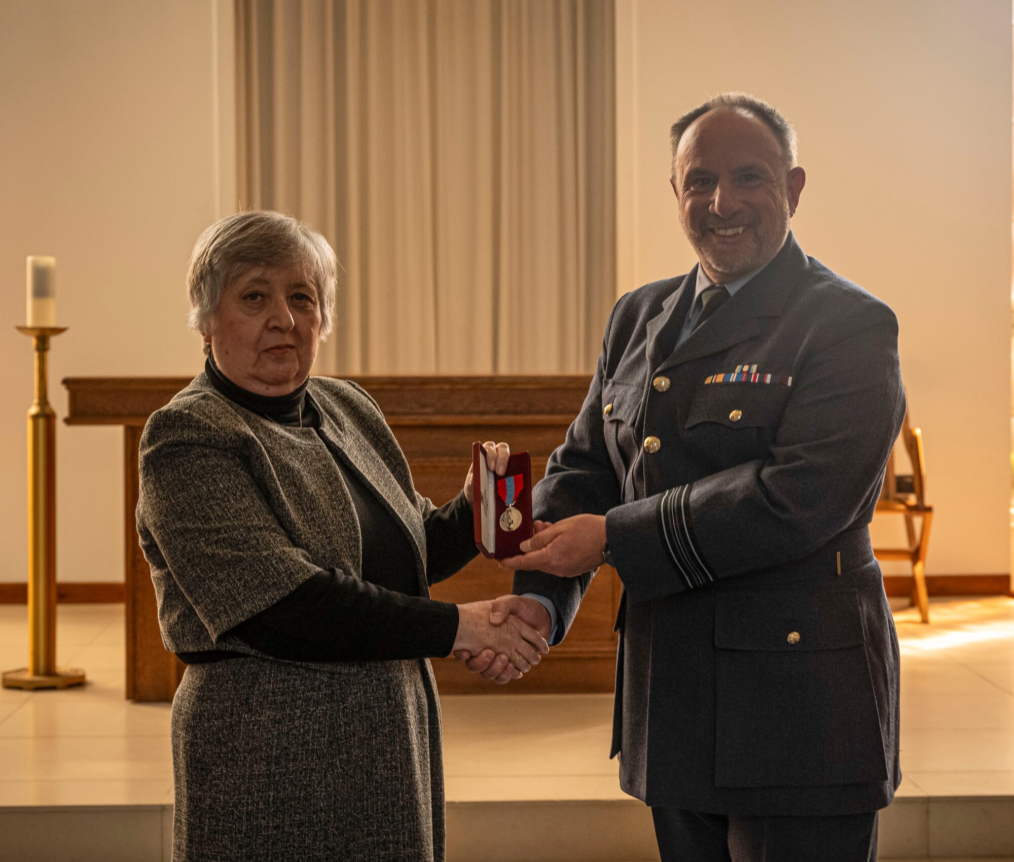 Sqn Ldr Andrew Bell, right, RAF Mildenhall commander, presents Nancy Tarling-Parker, retired Ministry of Defence civil servant, with the Imperial Service Medal at RAF Mildenhall, England, April 29, 2025.