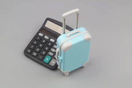 Calculator and travel suitcase on gray background