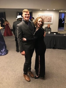 Male Solider in civilian suit pose with a woman in ball dress.