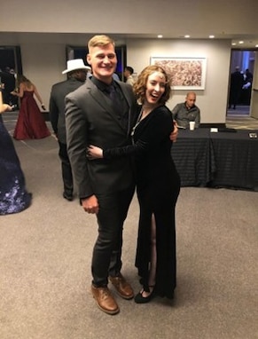 Male Solider in civilian suit pose with a woman in ball dress.