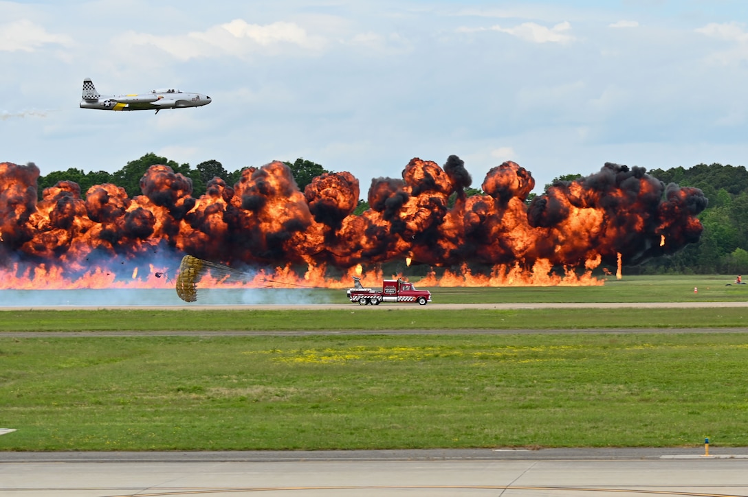 A truck and a plane race in front of an explosion.