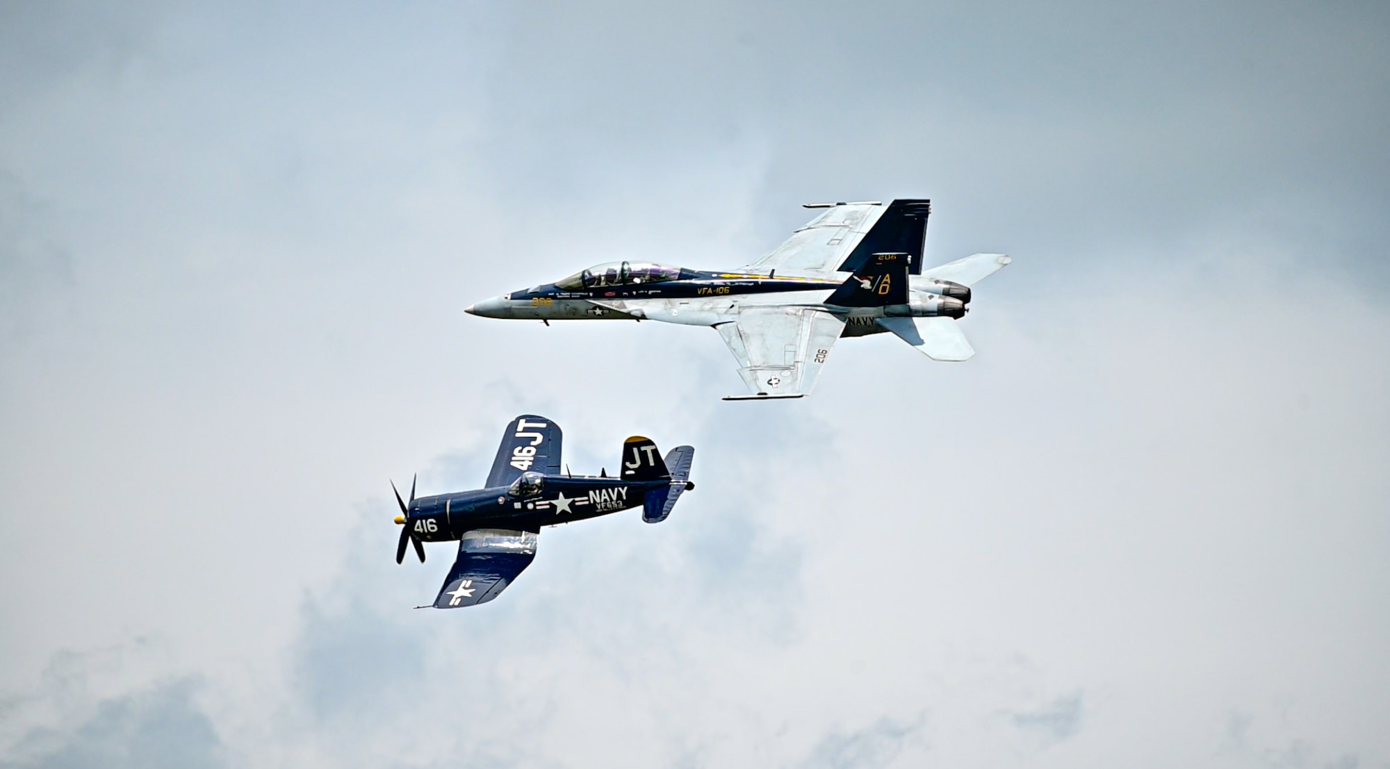 Two different planes fly next to each other in the sky.