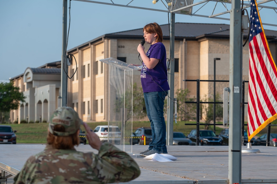 Operation KIDS participant sings the national anthem outside the Vance Deployment Center, Goodfellow Air Force Base, Texas, April 26, 2025. Following the national anthem, an invocation from Capt. Robert Joiner, 17th Training Wing Chaplain, a safety briefing from Master Sgt. Antonio Gonzales, 17th Communications Squadron first sergeant and remarks from Col. Angelina Maguinness, 17th Training Wing commander, were given to the participants. (U.S. Air Force photo by Airman 1st Class James Salellas)