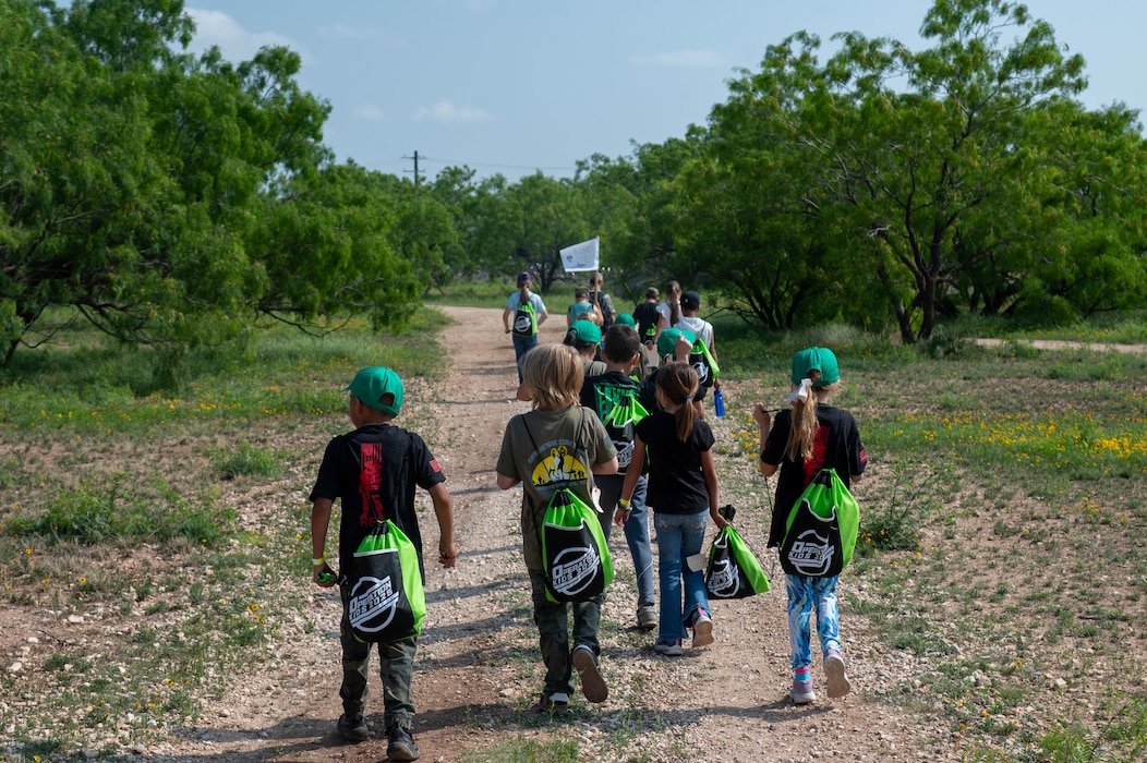 Operation KIDS participants walk the Forward Operating Base Sentinel trails as part of their simulated deployed environment exercise at Goodfellow Air Force Base, Texas, April 26, 2025. The annual event allows children to explore aspects of deployed life through interactive activities. (U.S. Air Force photo by Airman 1st Class James Salellas)
