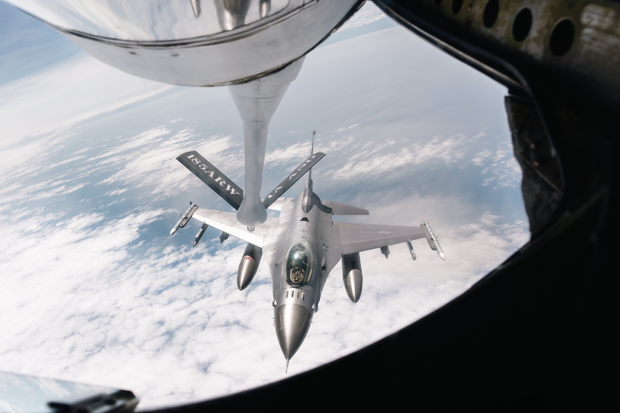 A grey fighter jet approaches the boom pod a KC-135 Stratotanker
