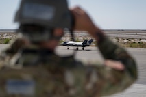A photo of an Airman looking through binoculars at an F-35 in the background