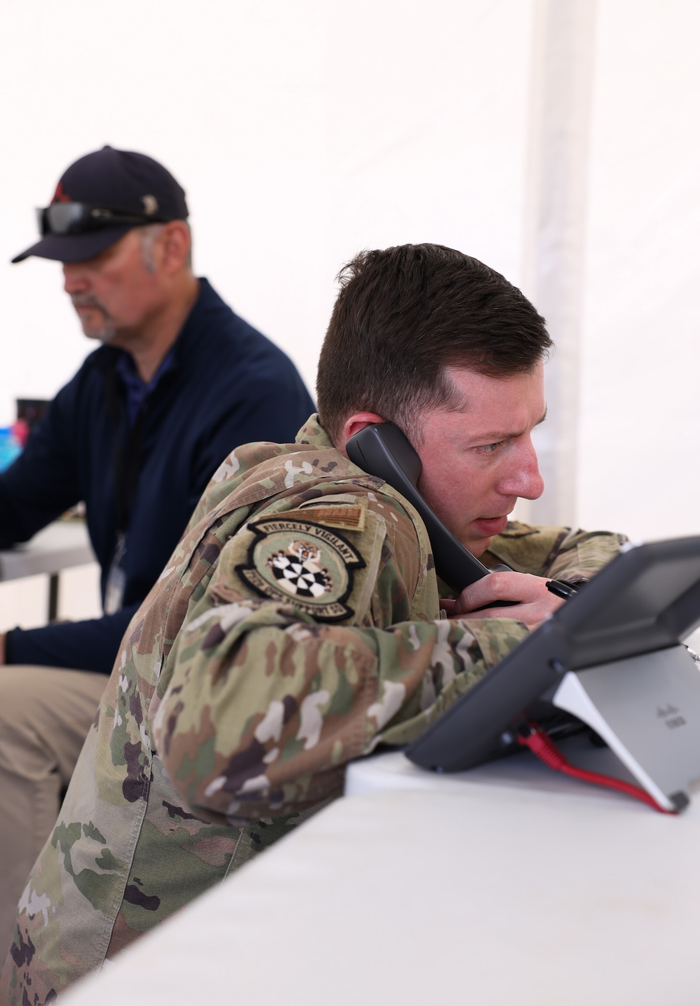 Tech. Sgt. Peyton Shaffer, non-commissioned officer for the 752 Operational Support Squadron weapons and tactics, answers a call from operators at the Shadow Operations Center-Nellis, Nellis Air Force Base, Nevada, during Project Convergence Capstone 5 at the National Training Center, Fort Irwin, California, March 10, 2025. The TOC-L integrates data from multiple sources to create a synchronized air picture, improving the speed and accuracy of command and control. (Official Air Force Photo by Morgan Brown).