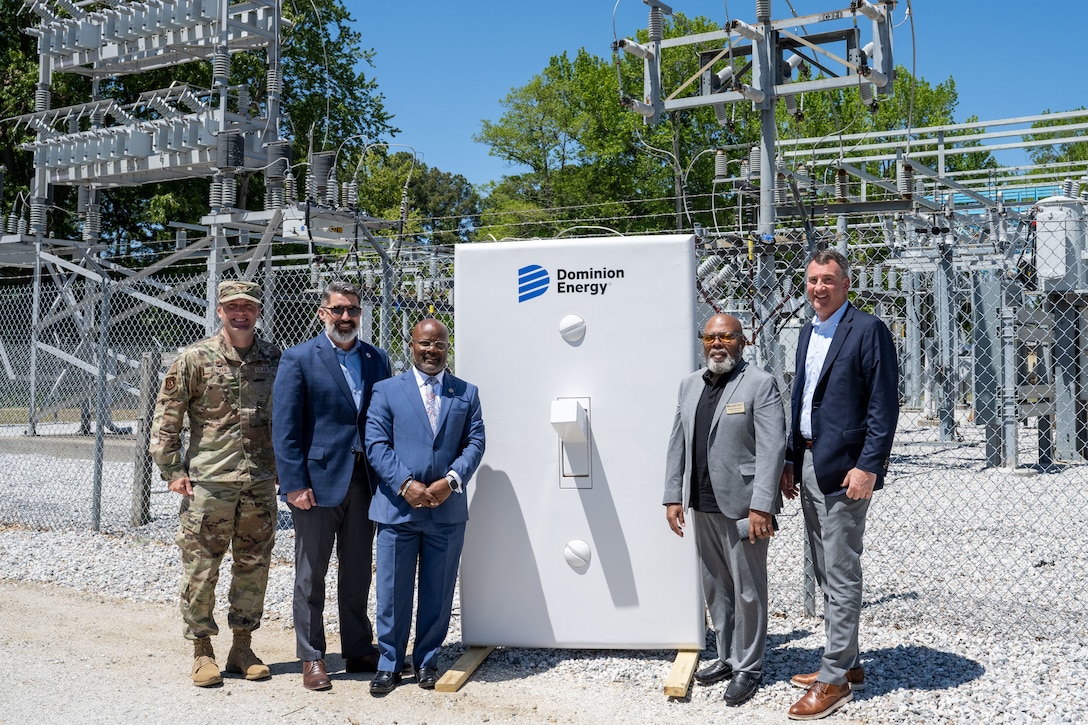 Five men stand around a large white light switch.