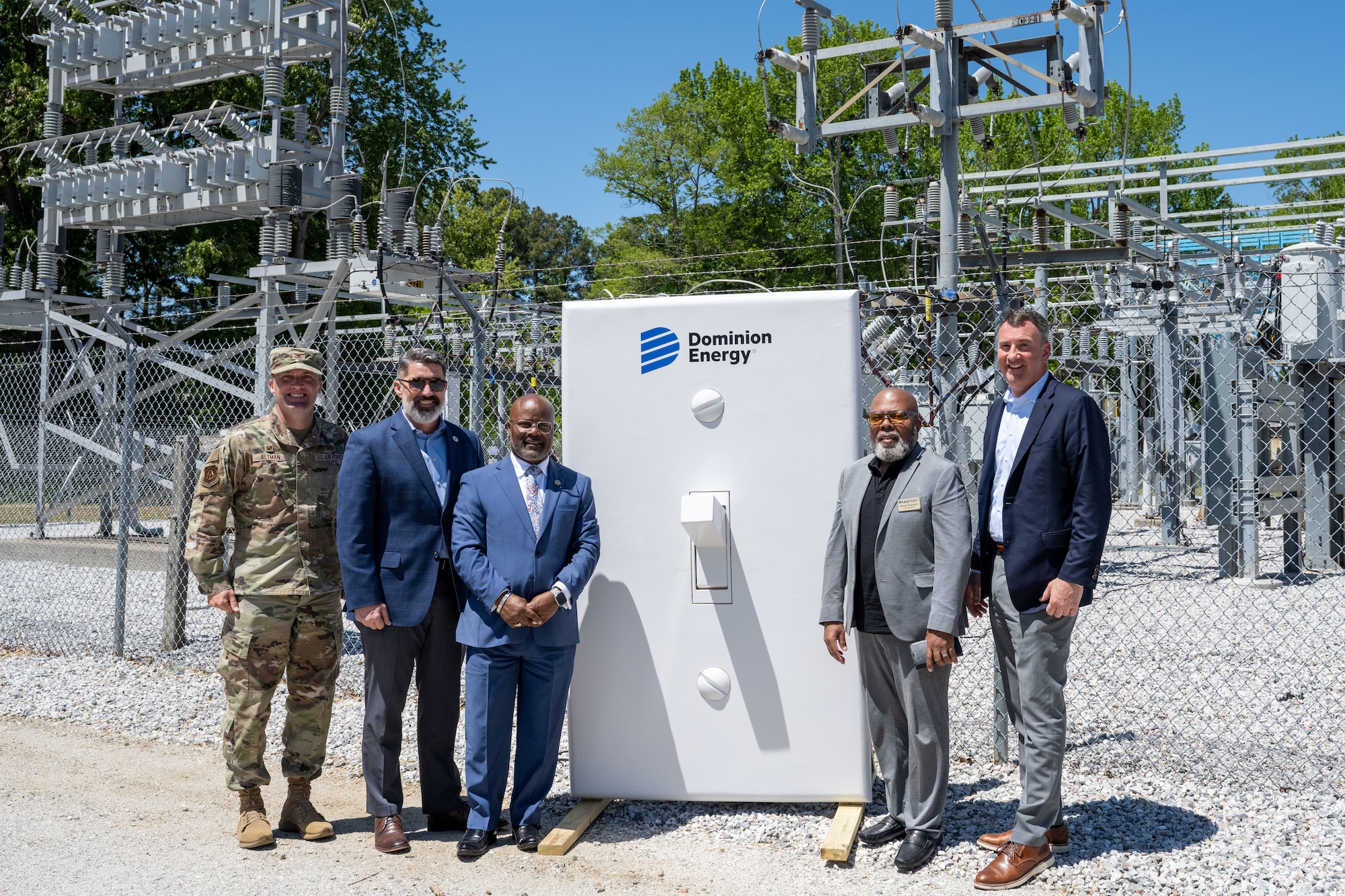 Five men stand around a large white light switch.
