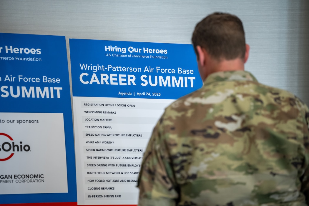 A uniformed service member stands in front of a Hiring Our Heroes schedule board