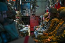 Many Airmen sitting inside a plane.