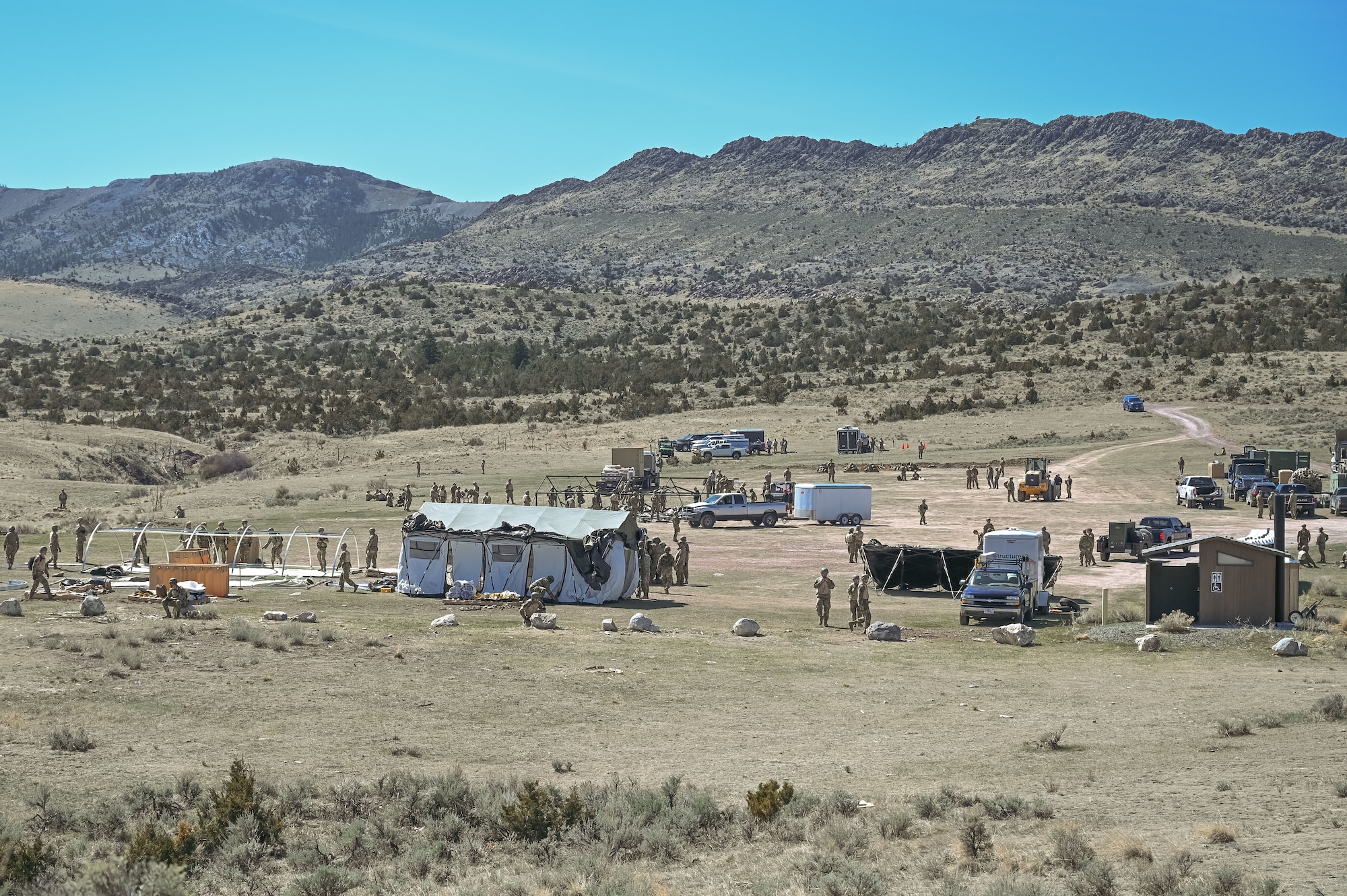 Field with vehicles, tents, and Airmen.