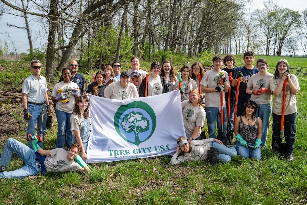 A group photo of volunteers posing with a Tree City USA white flag