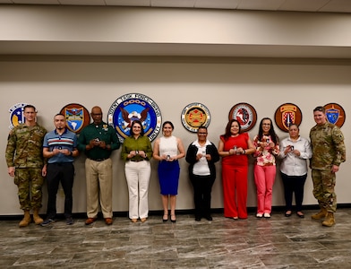 Foreign Service Nationals pose with Maj Gen Ryan and Command Sergeant Major Olson after receiving challenge coins for their hard work.