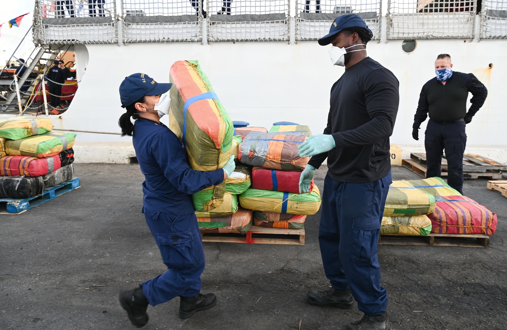 A USCGC Tampa (WMEC 902) crew member passes a bale of illicit drugs to another crew member during a drug offload at Port Everglades in Fort Lauderdale, Florida, April 30, 2025. The crew offloaded 59 bales of illicit drugs worth more than $12 million resulting from two interdictions in the Caribbean Sea by the crew of USS Minneapolis-Saint Paul and their embarked Navy helicopter. (U.S. Coast Guard photo by Petty Officer 1st Class Diana Sherbs)