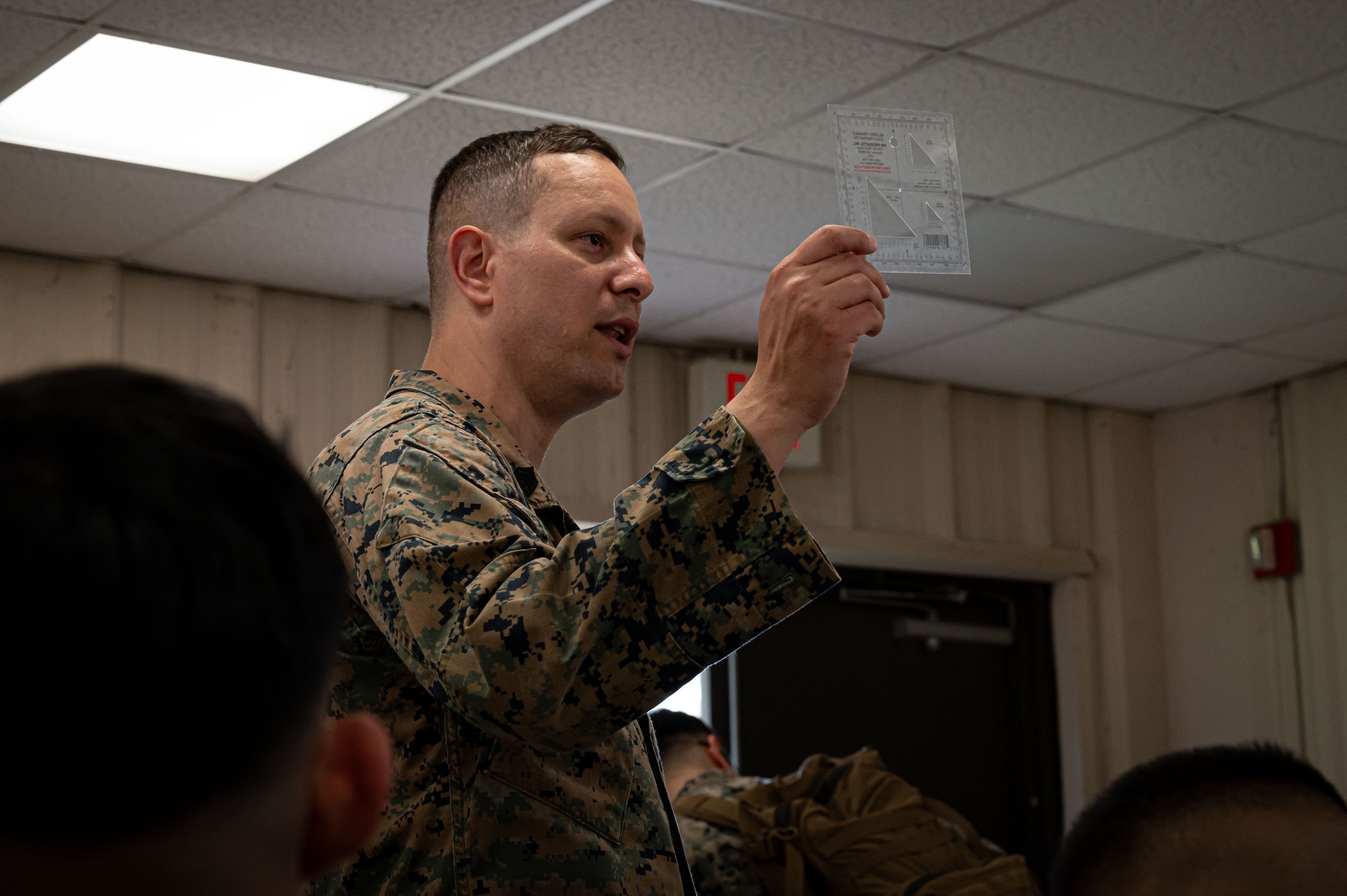 U.S. Marine Corps Gunnery Sgt. Mauro Feliz, Marine Aircraft Group 49 information security technician, explains how to effectively use a protractor for land navigation at Joint Base McGuire-Dix-Lakehurst, N.J., April 25, 2025. MAG-49 Marines trained in weapons qualification, land navigation and Chemical, Biological, Radiological, and Nuclear (CBRN) defense as a part of routine training.(U.S. Air Force photo by Airman 1st Class Luisa E. Dugan