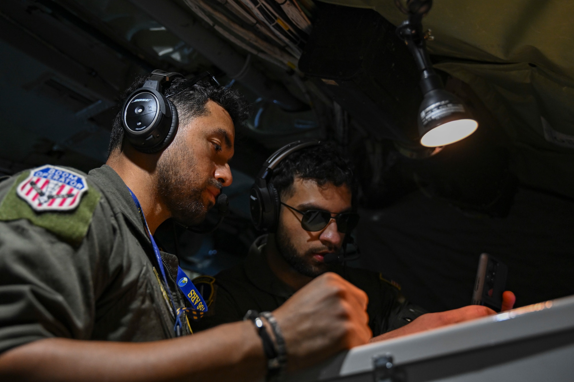 U.S. Air Force Staff Sgt. Elisaul Penafiel Alvarez, left, and Senior Airman Ata Chaudhry, both boom operators assigned to the 756th Air Refueling Squadron, review refueling plans aboard a KC-135 Stratotanker, April 22, 2025. The 459th ARW supports both training and operational missions worldwide, enhancing U.S. Air Force mobility and readiness. (U.S. Air Force photo by Senior Airman Gianluca Ciccopiedi)