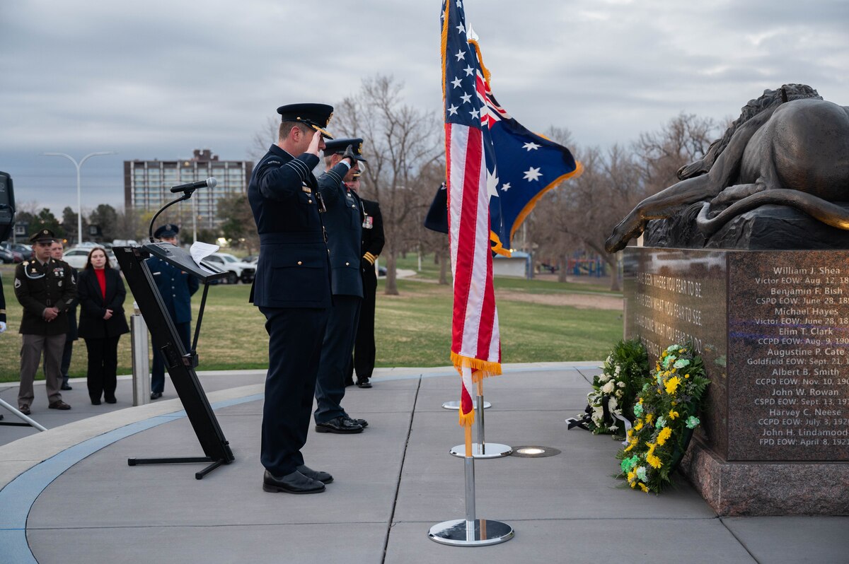 Col. Edgar Gonzalez and Lt. Col. Mark Waters salute the flower wreaths they have placed at a memorial site.